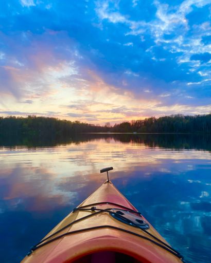 A vertical shot of a beautiful sunset over a pond from a kayak