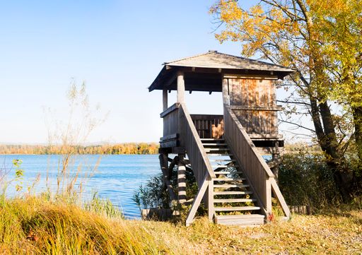 A wooden cabin by the shore of a lake on a sunny morning