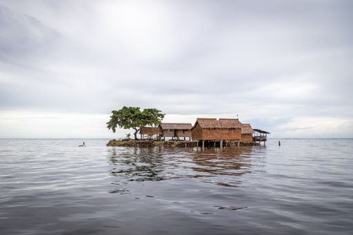 Traditional thatched houses built on a man-made island in the shallow waters of Lau Lagoon, on the eastern coast of Malaita Province, Solomon Islands.