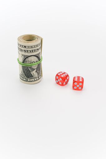 US dollar banknotes rolled up and red dice on a white tabletop with text space