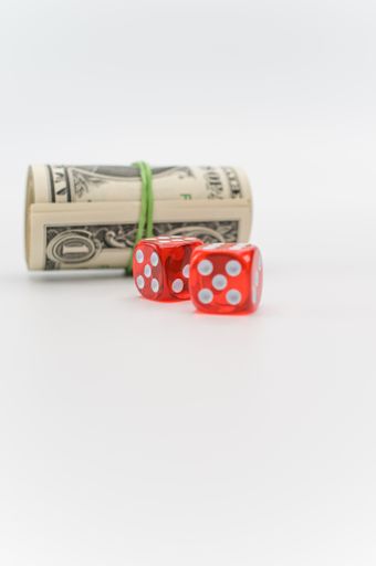 US dollar banknotes rolled up and red dice on a white tabletop with text space