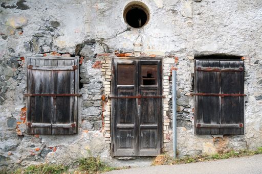 Old dirty door, two windows and dirty walls of an old building in Merano, South Tirol, Italy