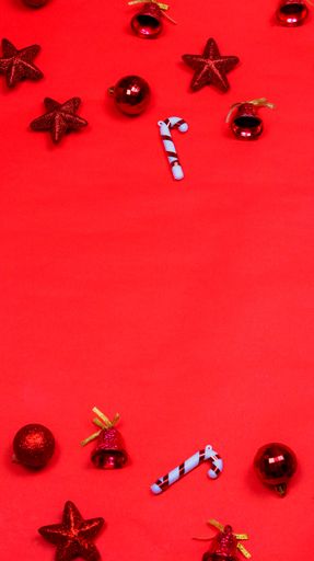 A vertical shot of Christmas tree toys on a red background with copy space
