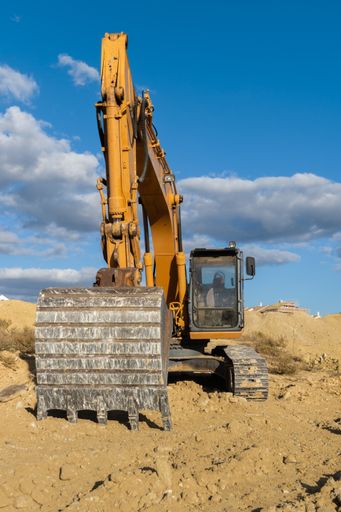 large yellow excavator working on the construction site moving earth