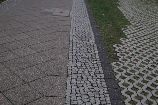A beautiful shot of a Detailed closeup texture on a cobblestone street with different tiles and grass