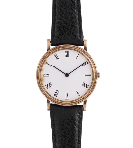 A closeup shot of a golden watch with black leather band isolated on a white background