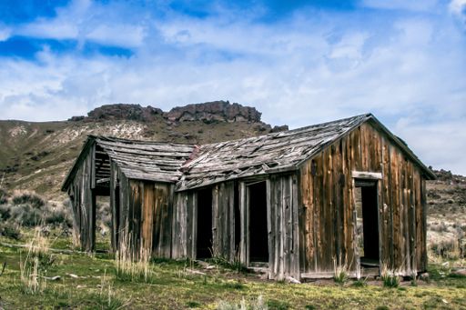 A wide shot of weathered wooden barns near mountains