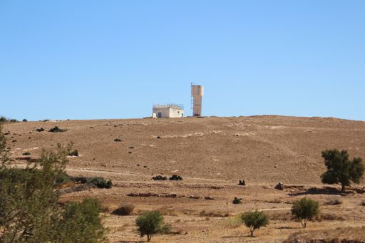 A low angle shot of a deserted hill with an industrial structure in the background