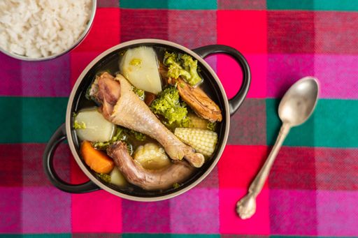 An overhead shot of Honduran chicken soup on a multicolored surface
