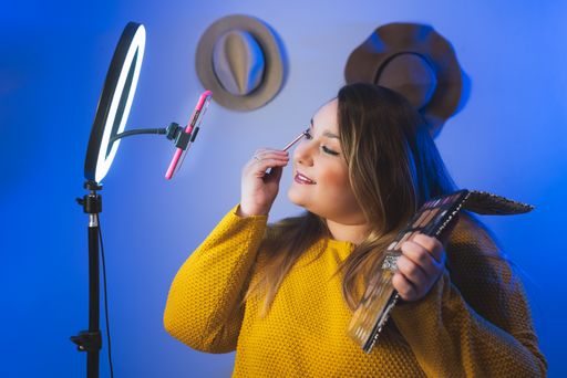 A shot of a Caucasian woman makeup artist video blogger shooting a video