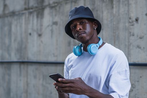A closeup of a man with white t shirt and a blue headset standing in the street and using phone, Spain