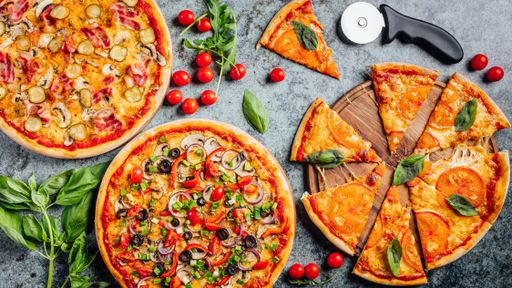 A high angle shot of freshly baked pizzas on a grey backgroun