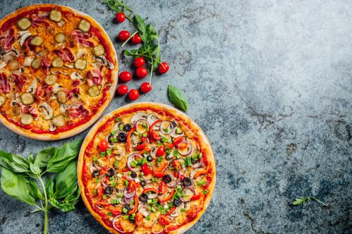 A high angle shot of freshly baked pizzas on a grey background with a copy space