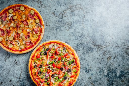 A high angle shot of freshly baked pizzas on a grey background with a copy space