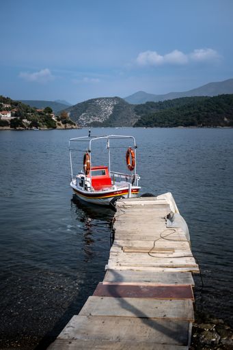 A fishing boat tied on a small wooden pier on a sunny morning