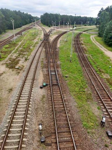 A beautiful low aerial view of empty metal railway with mossy grass with green trees and a hazy sky