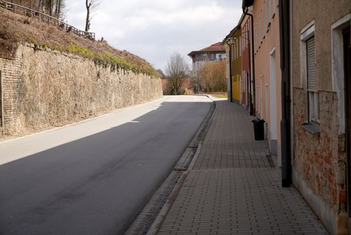 An empty street surrounded by buildings with shadow and sunlight