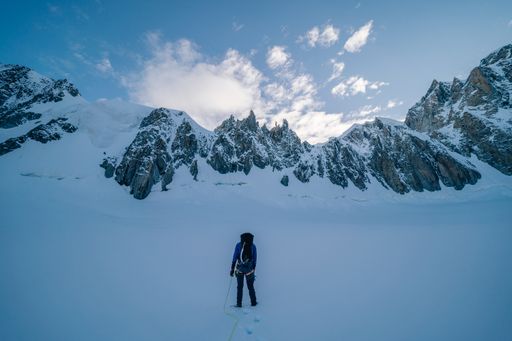 An Alpinist walking on a glacier. Mountaineering in Mont Blanc Masiff, high mountain alpine landscape with snow, ice and high peaks. Climber with rope