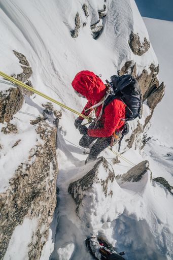 Winter mountaineering, alpinism in Mont Blanc Masiff, France. An alpinist descending on a rope from a mountain.