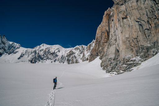 An Alpinist walking on a glacier. Mountaineering in Mont Blanc Masiff, high mountain alpine landscape with snow, ice and high peaks. Climber with rope