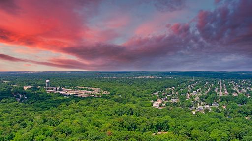 A mesmerizing view of a beautiful field surrounded by trees during a scenic sunset