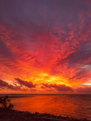 A mesmerizing scene of silhouetted boat in the water against an orange cloudy sky at sunset