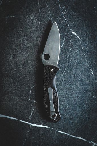 A top view of a folding knife on a marble surface