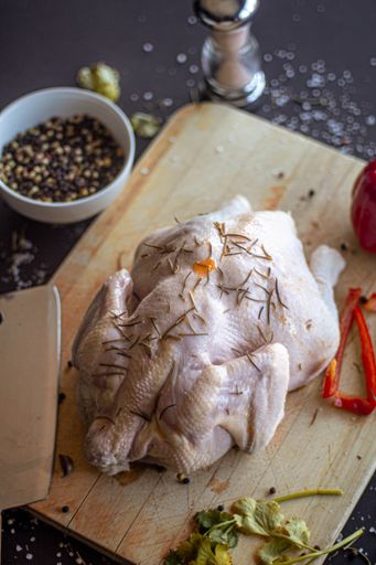A vertical shot of chicken meat on a board in a kitchen