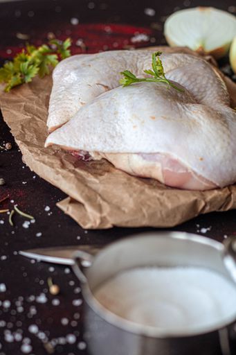 A vertical shot of chicken meat on a board in a kitchen
