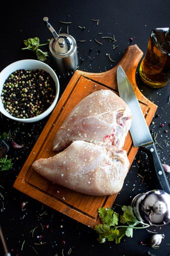 A vertical shot of chicken meat on a board in a kitchen