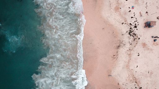 A top view of foam waves hitting a sandy seashore