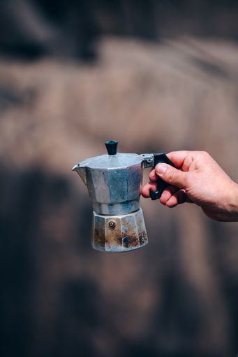 A vertical shot of a hand holding a small silver moka pot