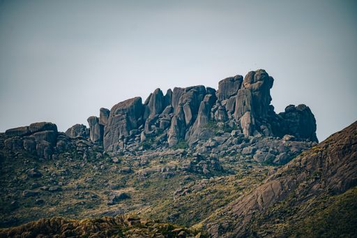 A view of rocky mountains with plants against a gray sky in Itatiaia National Park, Brazil