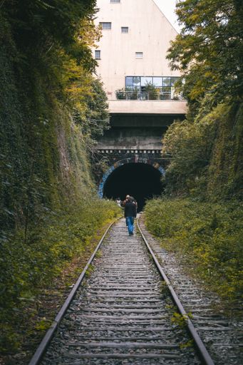A vertical shot of a man walking on a railway