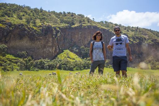 A couple standing on a green field near the cliffs in Naivasha Hells Gate National Park, Kenya