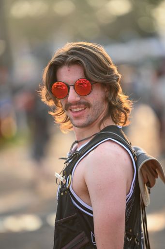 A vertical shot of a cool young male with long hair and red sunglasses