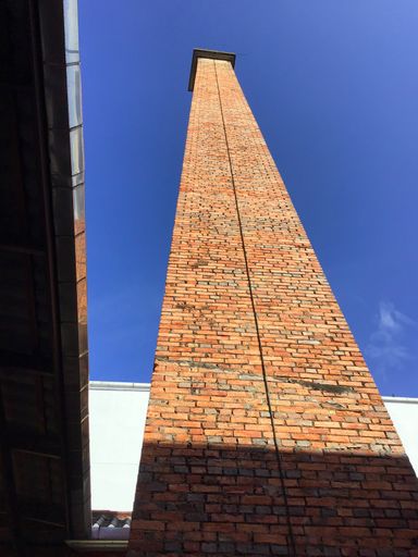 A low angle shot of the red brick tower against a clear blue sky in Songkhla Province, Thailand