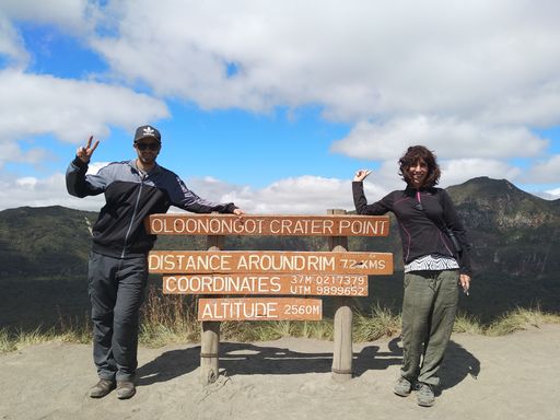 A couple standing by the wooden sign of Longonot National Park captured in Longonot, Kenya
