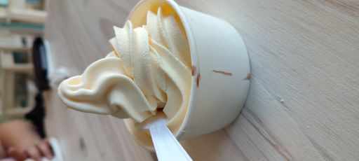 A vertical shot of vanilla ice cream on a styro cup with spoon