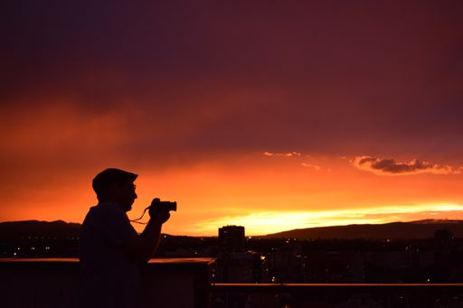 A silhouette view of a male shooting by a camera with an orange sunset