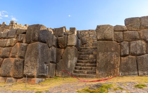 Ancient Inca stone walls at Sacsayhuaman, Cusco, Peru, under a clear blue sky, showcasing intricate masonry.