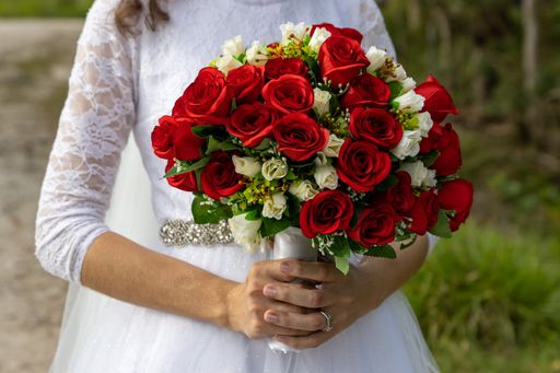 A closeup shot of bride hands holding a bouquet of red roses on a wedding day