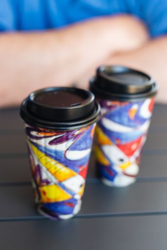 A vertical selective closeup shot of two colorful takeaway cups