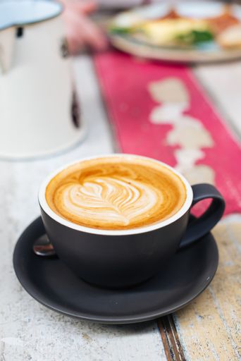A vertical selective closeup shot of latte art coffee in a black ceramic cup