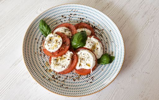 Caprese salad plating fresh mozzarella, sliced tomato, basil leaves, olive oil, and spices