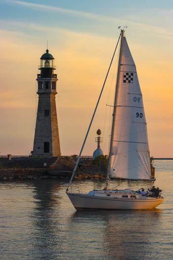 A sailing boat in the ocean by Buffalo main lighthouse at scenic sunset, United States of America