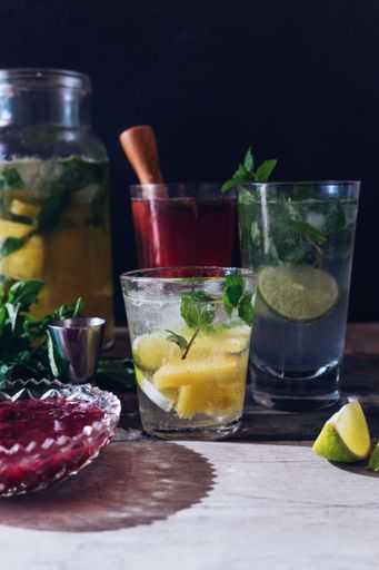 A vertical selective closeup shot of ice lemonades with lemon and lime in drinking glasses