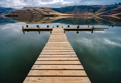 A beautiful view of a wooden dock by the lake under a cloudy sky, KZN, South Africa