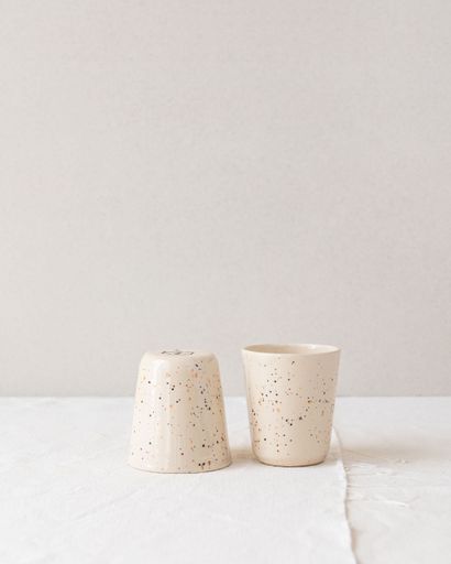 Minimalist ceramic cups with speckled design on a neutral background, showcasing modern home decor style.