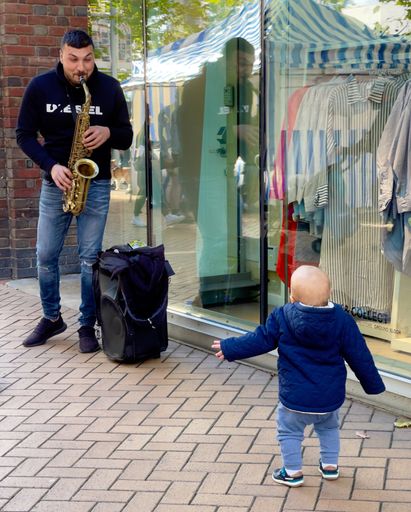 A vertical shot of cute baby dancing to street music in the United Kingdom
